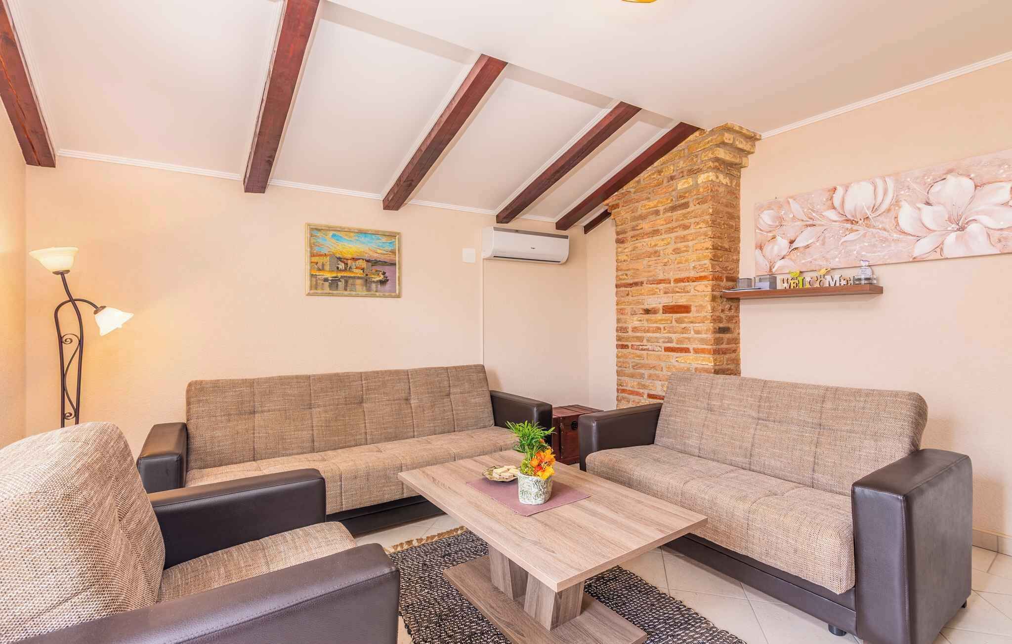 Ein Wohnzimmer mit einer Sofagarnitur, einem Couchtisch mit Blumenvase, einem Bild an der Wand und einer Ziegelwand.