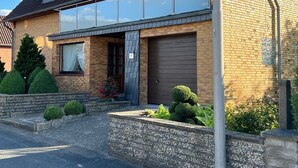 Una casa de dos pisos con garaje, un pequeño porche delantero y un jardín bien cuidado.
