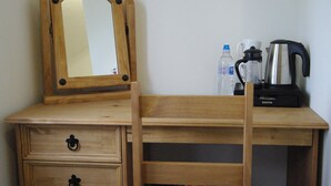 A wooden desk with a mirror, a coffee maker, and a water bottle. - Sandhill (Sandown)