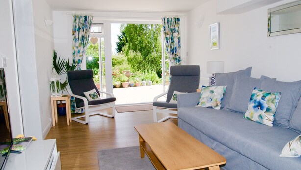 A living room with a grey sofa, two armchairs, a wooden coffee table, and a TV on a stand.