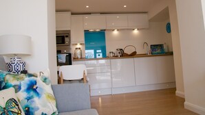A modern kitchen with white cabinets, a microwave, and a coffee machine.