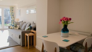 A modern living room with a sofa, a dining table, and a vase of flowers.