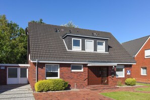 A two-story house with a dark roof, a brick facade, and a front door with a small porch.