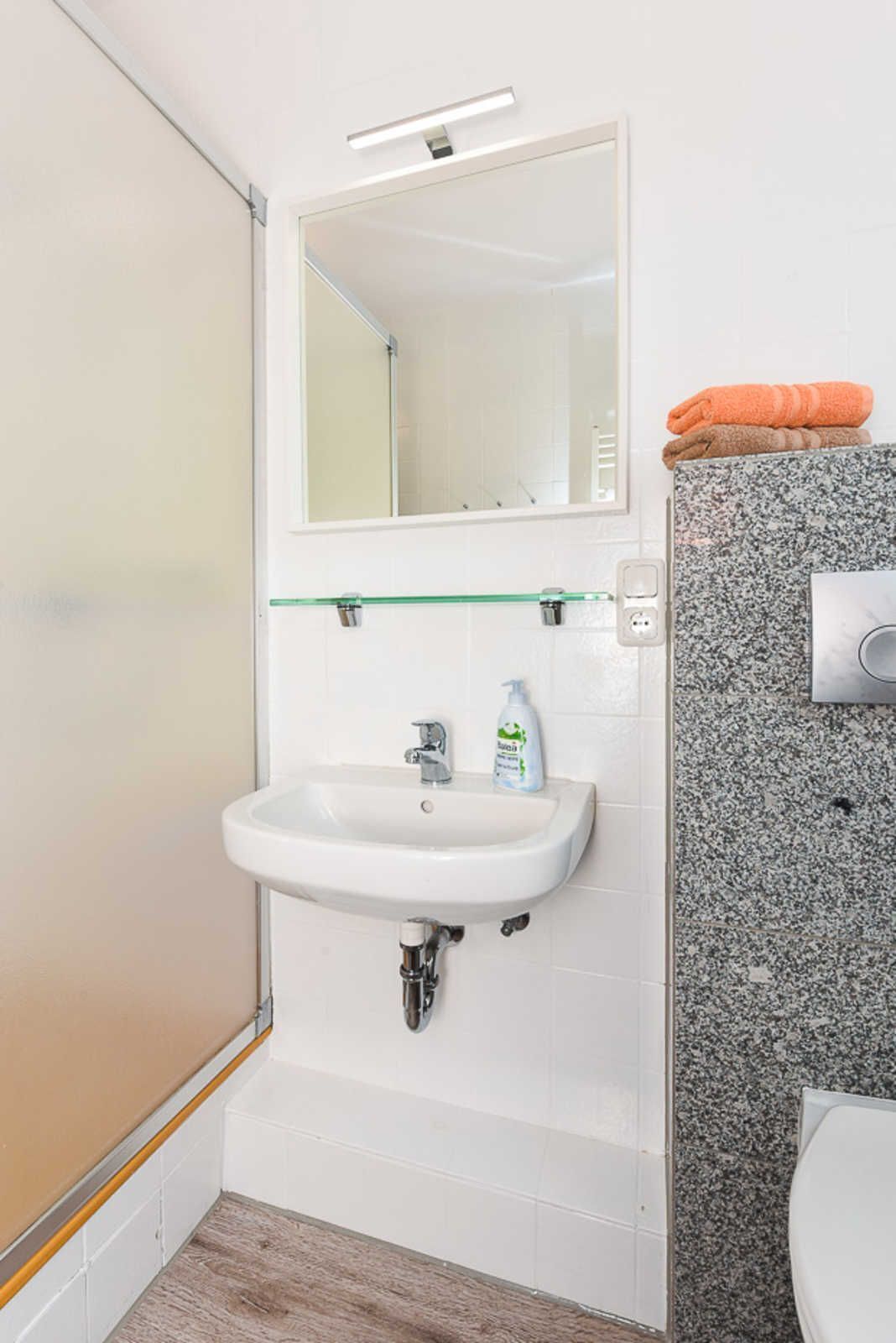 A bathroom with a white sink, a mirror, and a shower.