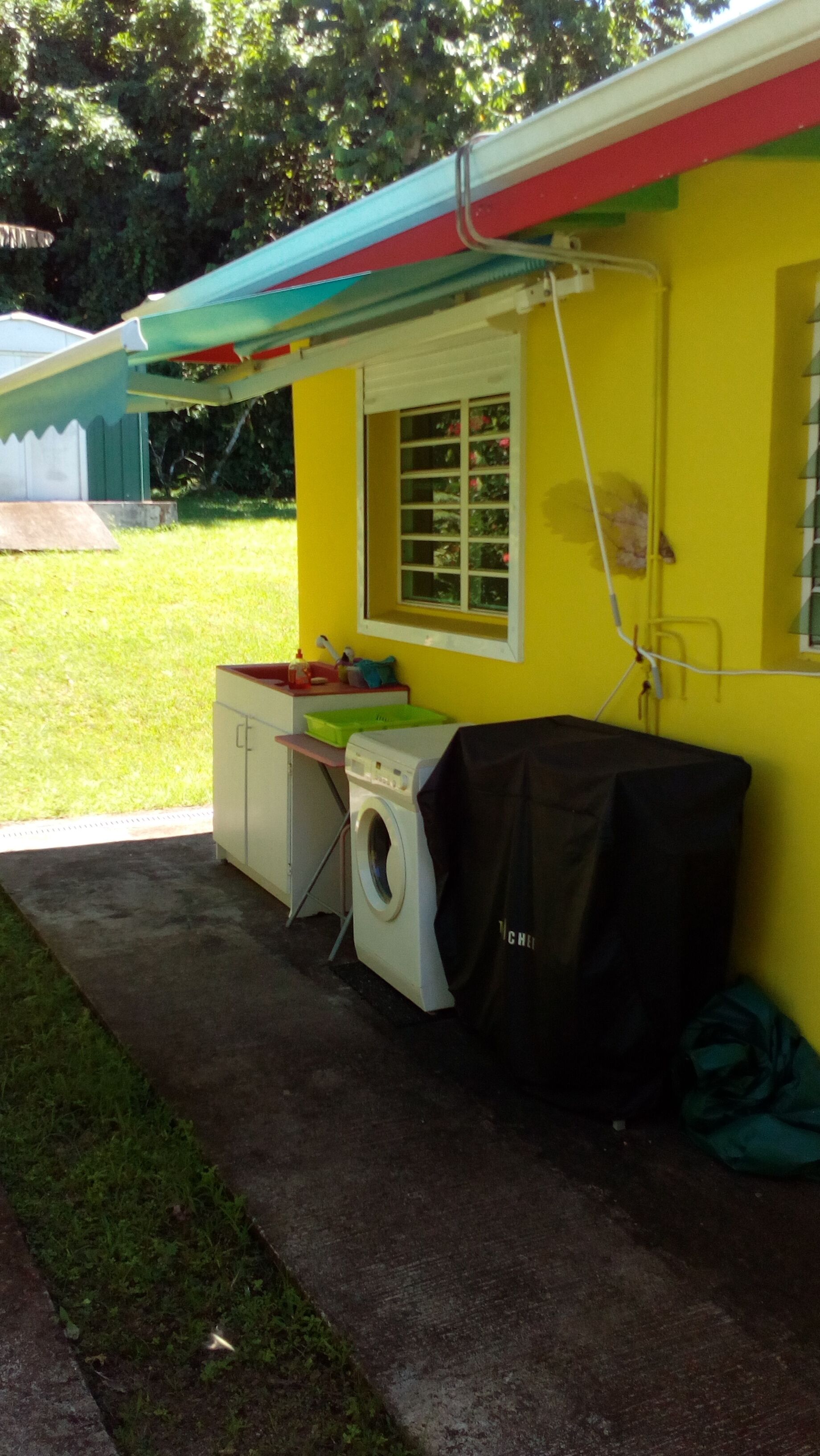 A laundry area with a washing machine, a drying rack, and a small window.