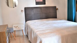 Un dormitorio con cama, mesita de noche, espejo y un cuadro en la pared.
