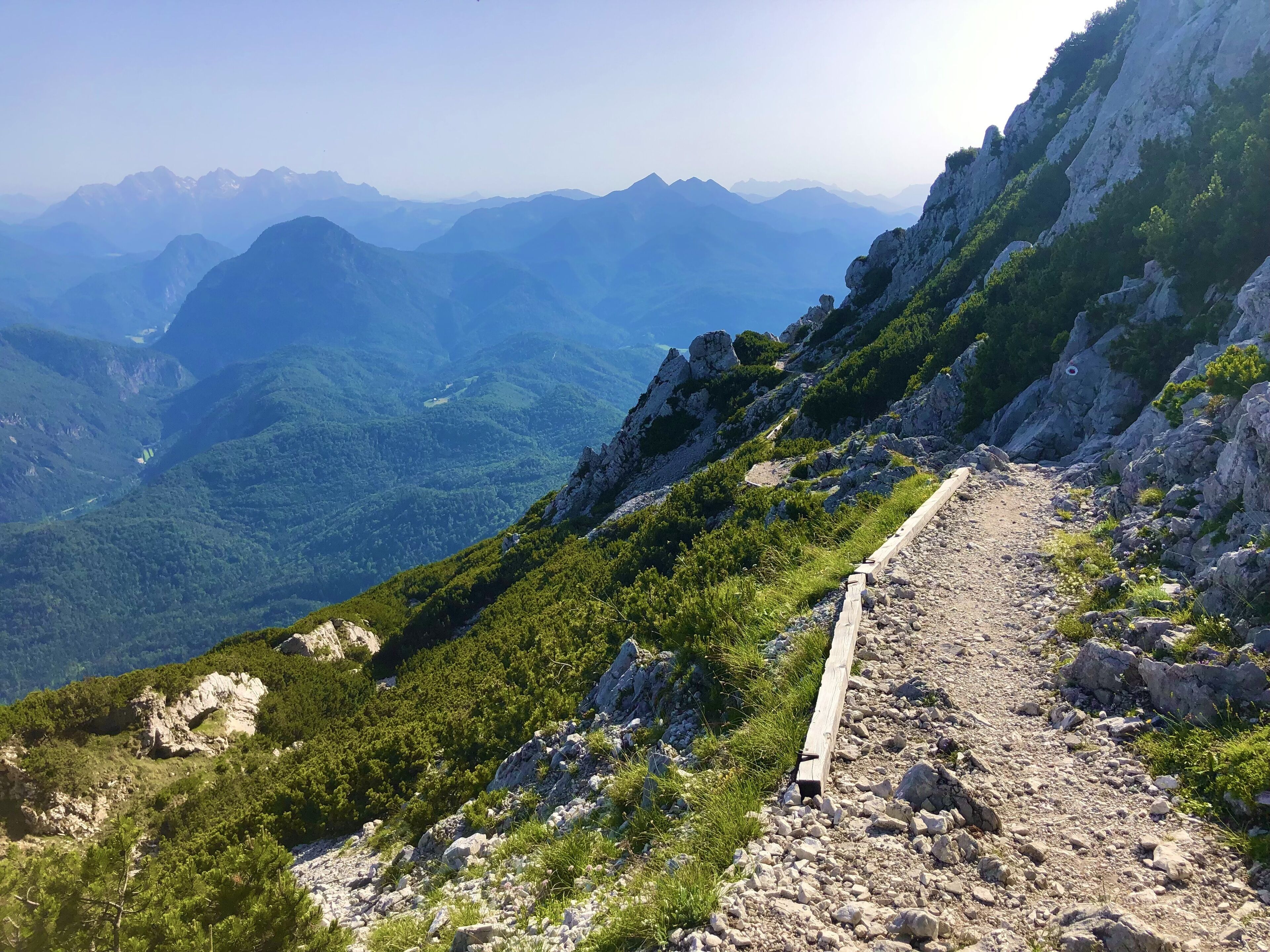 A mountain trail with rocky terrain and sparse vegetation.