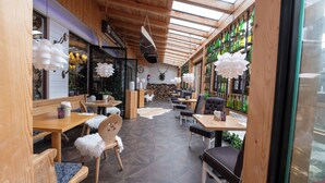 A cozy café with wooden furniture, a glass ceiling, and a variety of bottles on shelves. - Alpenliebe Design Hotel (Inzell)