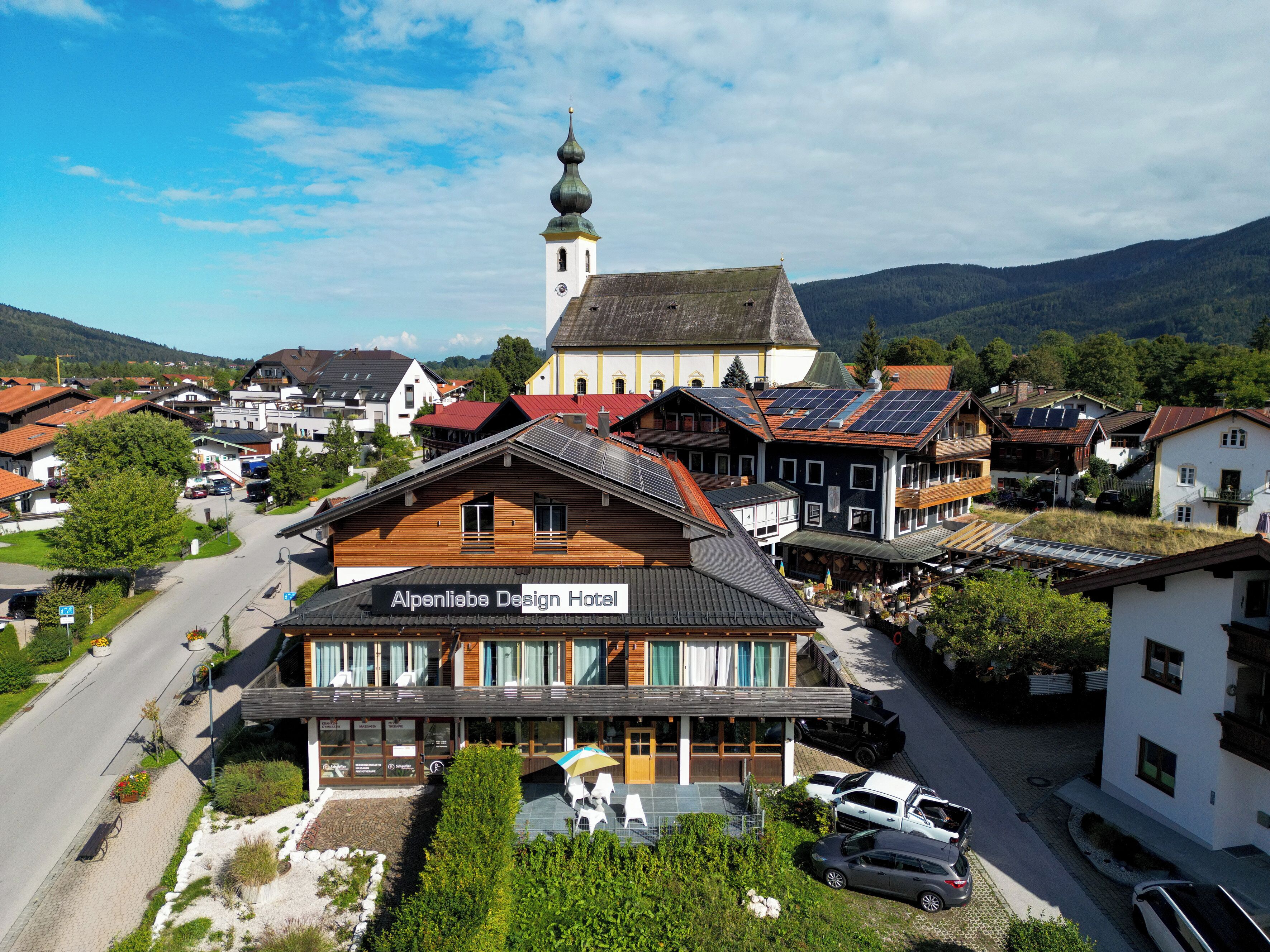 A hotel with a traditional Alpine design, featuring a prominent tower and a modern building with solar panels.
