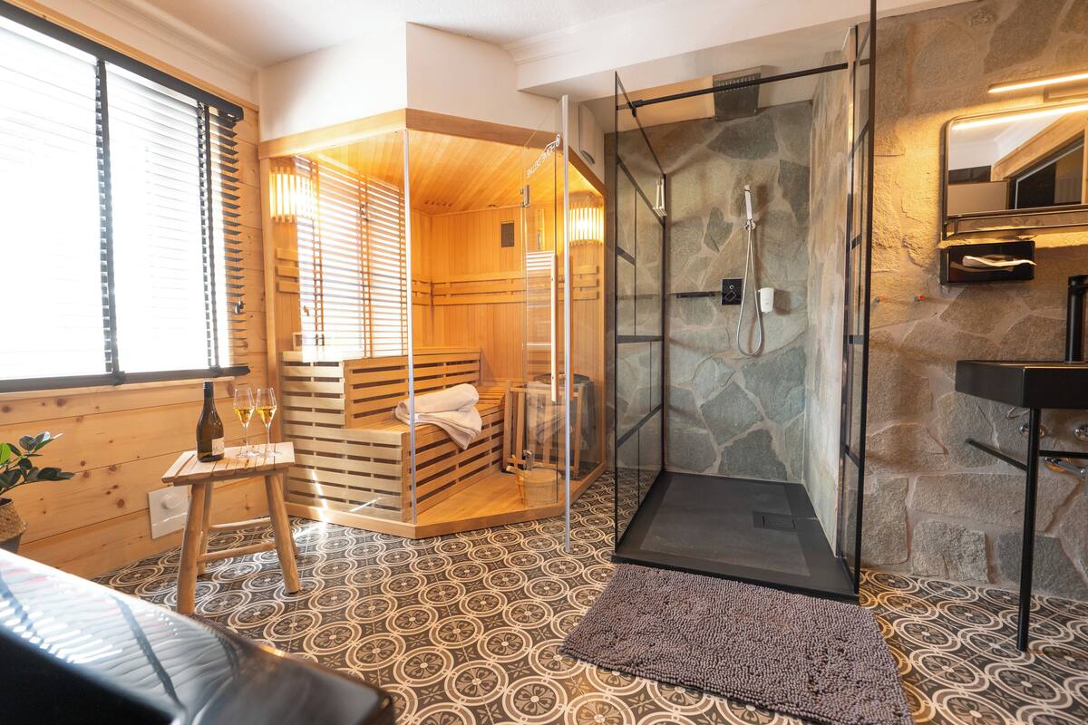 A sauna room with a wooden bench and a glass-enclosed shower area.