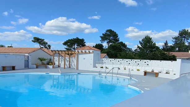 Piscina con una pérgola y una pared blanca con diseños decorativos.