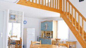 Una cocina con armarios de madera, un refrigerador y una zona de comedor con mesa y sillas de madera.