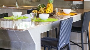 Un'isola nella cucina con un piano in granito, due sottopiatti verdi, una ciotola, un bicchiere e un'ananas.