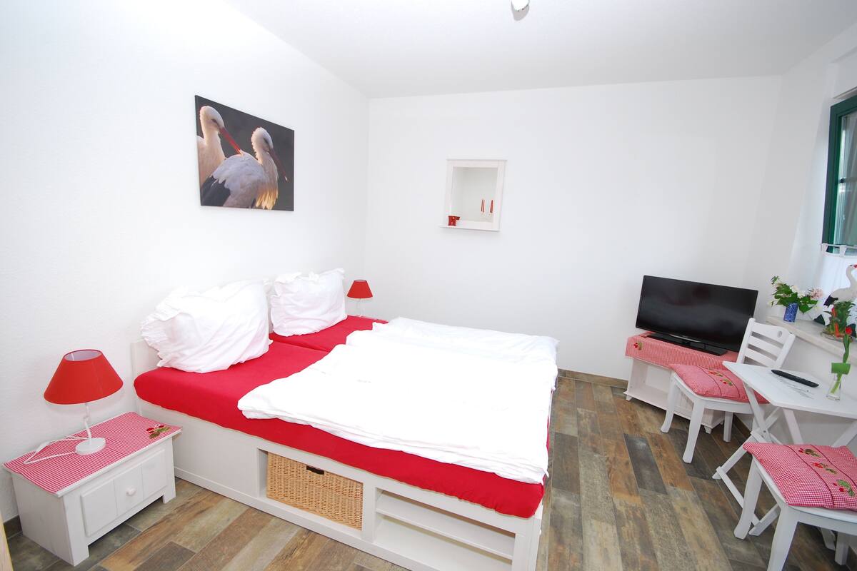 A bedroom with a bed, a TV, a desk, and a chair.
