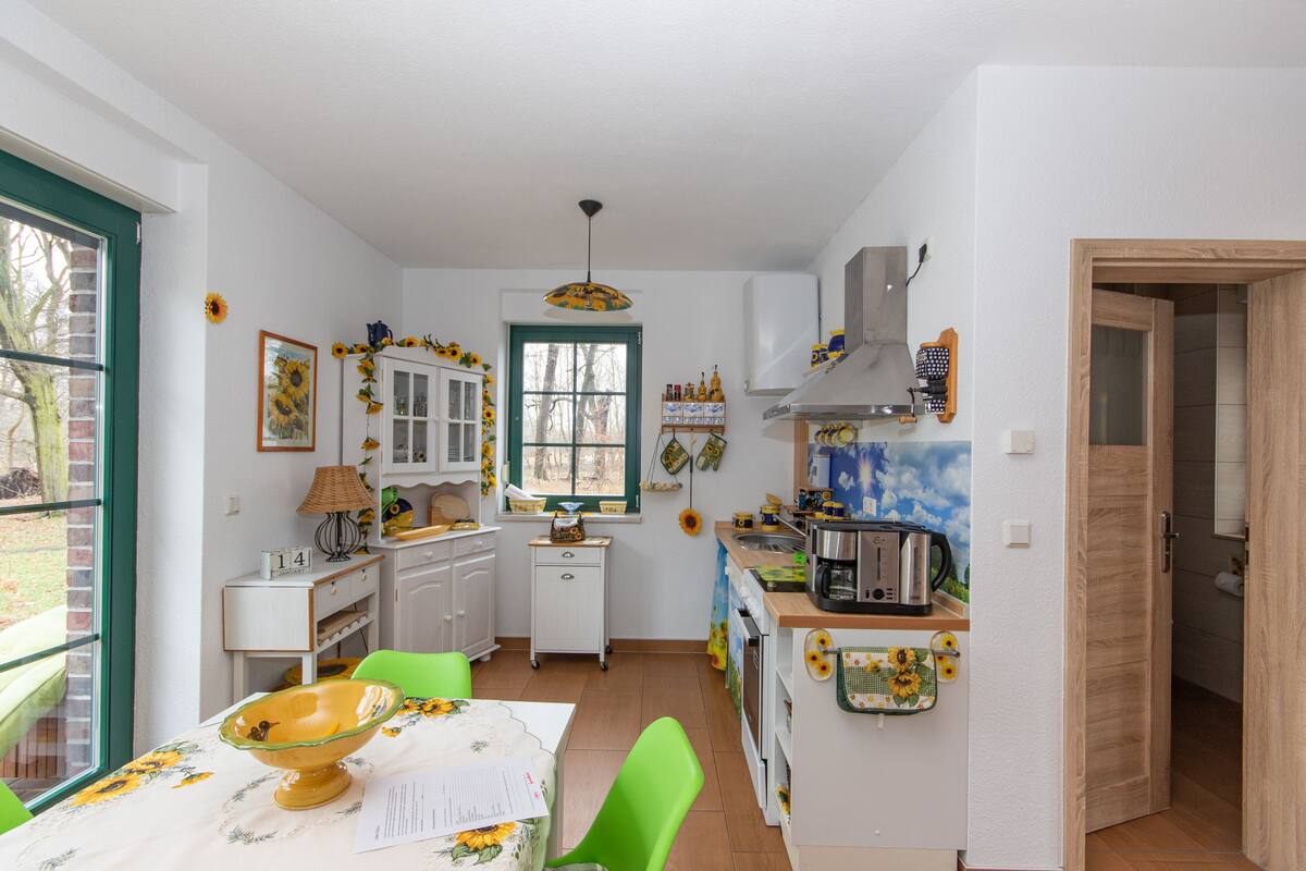 A compact kitchen with a dining area, a window with a view, and a door leading to another room.