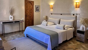A bedroom with a bed, bedside tables, a desk, and a door. -  riad with pool - Residence Ayda - Marrakech Palmeraie. near golf (MARRAKECH)