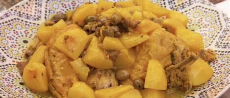 A plate of food with chunks of meat and potatoes, served on a decorative plate.