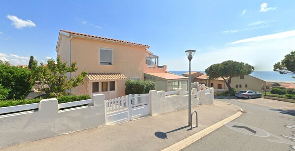 A residential street with houses, a white fence, and a lamp post.