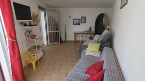 A living room with a sofa, a small table, a chair, and a TV. - Villa, all mod cons, enclosed with seaside view (Fleury)