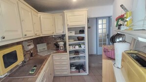 A kitchen with white cabinets, a yellow microwave, a built-in oven, and a pantry with dishes. - Villa, all mod cons, enclosed with seaside view (Fleury)