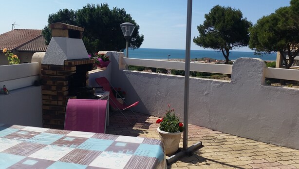 A terrace with a table, chairs, a potted plant, and a view of the sea. - Villa, all mod cons, enclosed with seaside view (Fleury)