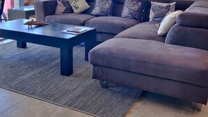 A modern living room with a large sectional sofa, a coffee table, and a view of the ocean.