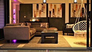 A modern living room with a sofa, armchair, and hanging chair, featuring abstract art on the walls.