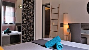 A hotel room with a bed, a desk, a chair, a lamp, and a mirror.