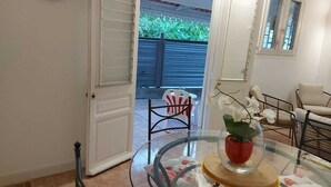An open door leading to a patio with a chair and a table with a vase of flowers.