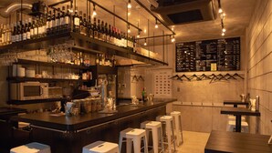 A bar area with multiple stools, a counter with bottles and glasses, and a menu board on the wall. - Smi:re Stay Oshiage (Tokyo)