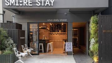 De ingang van SMI:RE STAY, met een modern ontwerp en een café, bar, delicatessenzaak en wijnsectie.