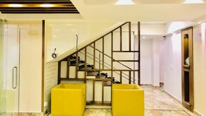 Un interior moderno con escalera, cabina de ducha de vidrio y asientos amarillos.