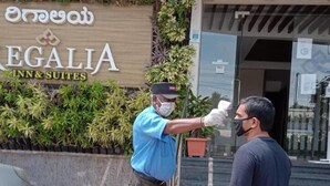 Un hombre siendo registrado por un guardia de seguridad en la entrada de un hotel llamado "EGALIA INN & SUITES".