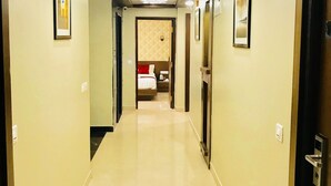 Un pasillo de hotel con un diseño moderno en el techo, cuadros enmarcados en las paredes y un suelo limpio y reflectante.