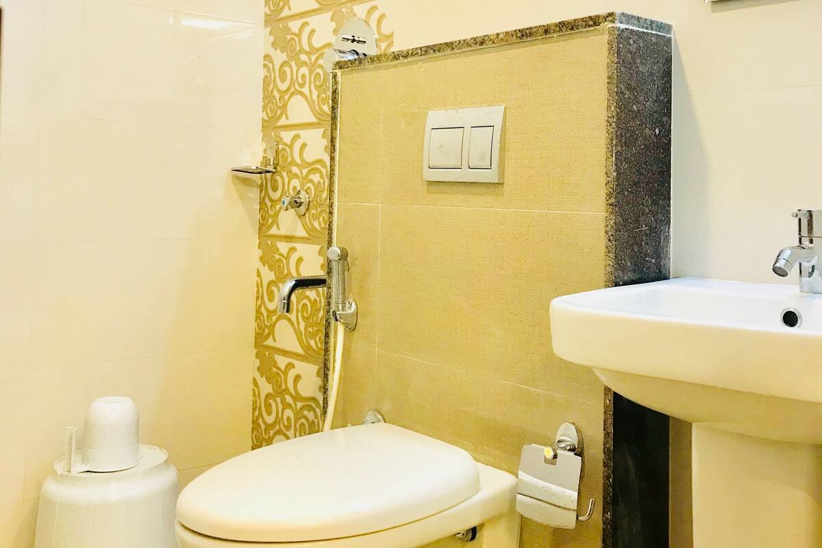 A bathroom with a toilet, bidet, sink, and a shower with a decorative wall.