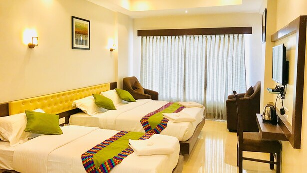 Habitación de hotel con dos camas, un escritorio y una silla.
