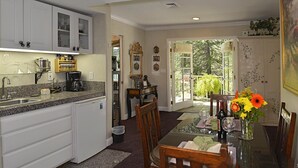 A kitchen with white cabinets, a granite countertop, and a dining area with a glass table set for two. - TRANQUJIL GARDEN STUDIO RETREAT,  W/HOT TUB
Minutes from Downtown Napa (Napa)