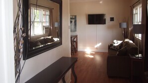 A living room with a large mirror, a flat-screen TV, and a sofa. - The Historic Clarkdale Lodge is your adventure headquarters! (Clarkdale)