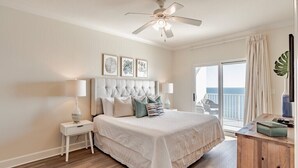 A bedroom with a bed, nightstands, a ceiling fan, and a view of the outdoors. - Seawind 1505 | Updated condo with perfect beach view and walk to dine, shop, more! (Gulf Shores)
