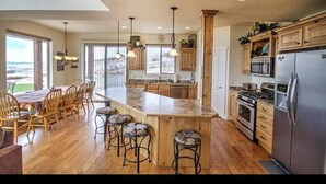 Una cocina amplia con una isla grande, armarios de madera y vistas al exterior.