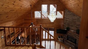A wooden cabin with a sloped ceiling, a chandelier, a fireplace, and a dining area. - 7 minutes to Parkway, hot tub, WiFi , pet friendly (Sevier County)