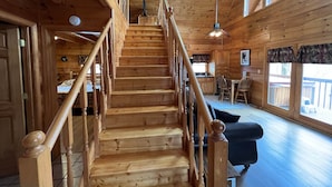 A wooden staircase with a railing leading to a dining area with chairs and a table. - 7 minutes to Parkway, hot tub, WiFi , pet friendly (Sevier County)