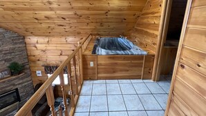 A wooden cabin with a stone fireplace, a small balcony with a hot tub, and a tiled floor. - 7 minutes to Parkway, hot tub, WiFi , pet friendly (Sevier County)