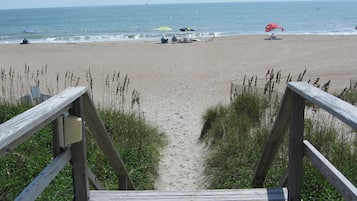 Une promenade en bois mène à une plage de sable, d’où l’on a une vue dégagée sur l’océan.