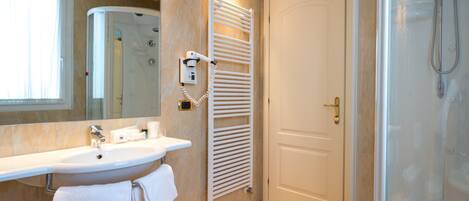 Un baño moderno con lavamanos, espejo, toallero y ducha.
