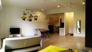 A modern living room with a sofa, a dining table, and a TV. There are ceiling fans and a kitchen in the background. - Cartoonstay Minion 01 Midhills Genting (Genting Highlands)