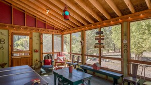 Une cabane en bois avec une table de ping-pong, des chaises et un banc.