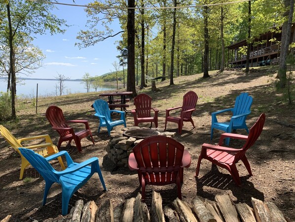A lakeside outdoor seating area with Adirondack chairs and a stone fire pit. - Get away from EVERYTHING! Secluded from the world. 300ft Water Front Log Cabin. (Quitman)