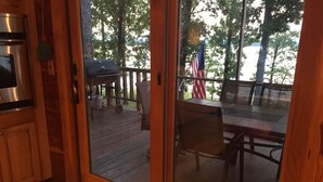 A wooden deck with outdoor furniture, a grill, and an American flag.