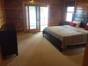 A bedroom with a bed, a dresser, and a sliding glass door leading to an outdoor area. - Get away from EVERYTHING! Secluded from the world. 300ft Water Front Log Cabin. (Quitman)